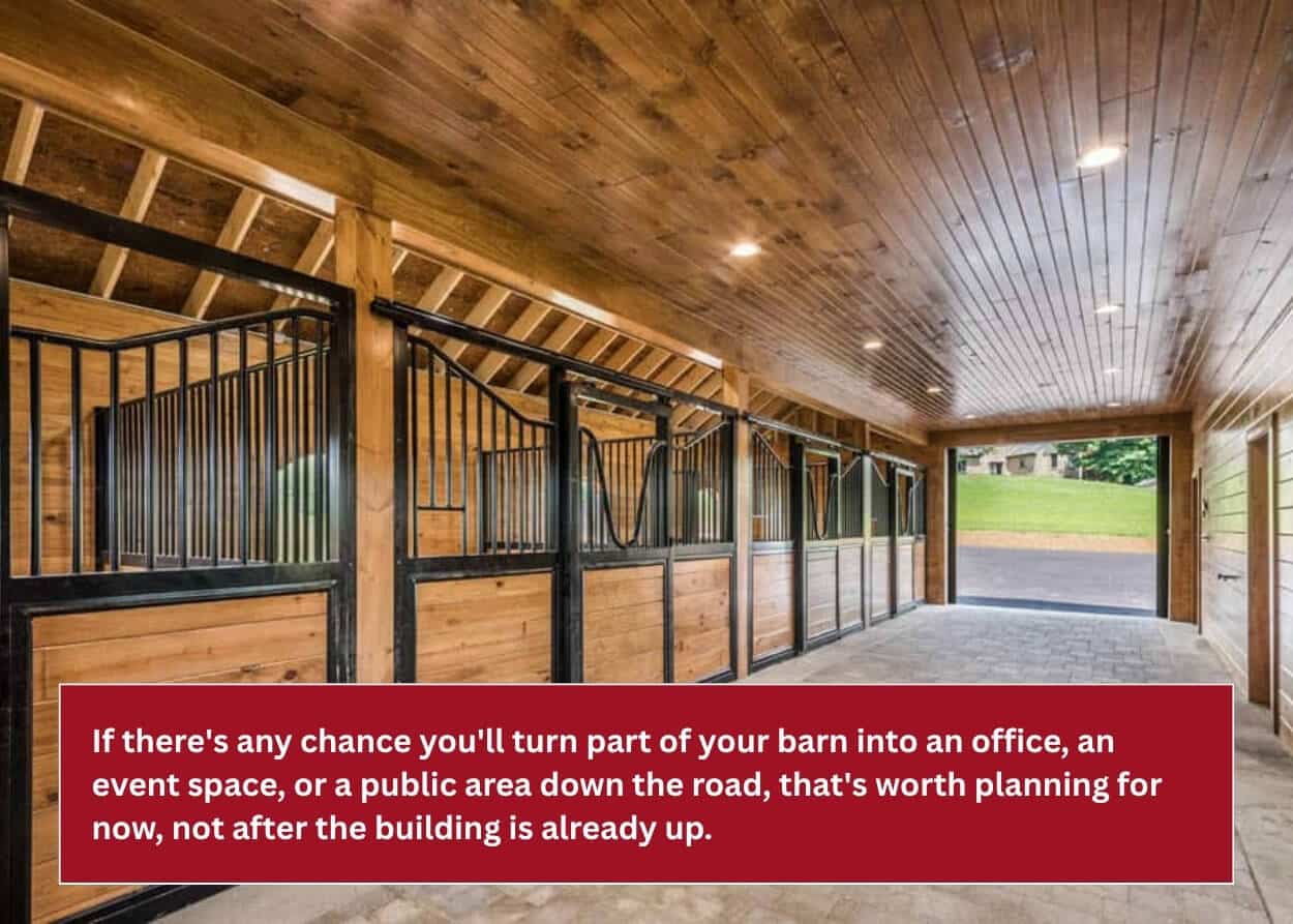 Modern horse barn interior featuring custom horse stalls, wood finishes, and a paved center aisle.